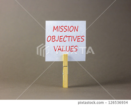 Mission objectives values symbol. Concept words Mission Objectives Values on beautiful white paper on clothespin. Beautiful grey background. Business mission objectives values concept. Copy space. Mission objectives values symbol. Concept words Mission Objectives Values on beautiful white paper on clothespin. Beautiful grey background. Business mission objectives values concept. Copy space. 126536934