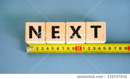 Next symbol. Concept word Next on beautiful wooden blocks. Beautiful yellow ruler. Beautiful blue table blue background. Business, lifestyle, support and next concept. Copy space. 126537038