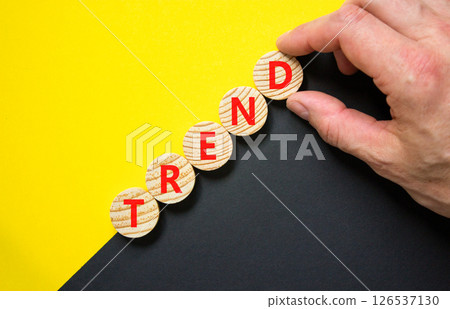 Trend and trending symbol. Concept word Trend on beautiful wooden circles. Beautiful yellow and black background. Businessman hand. Business lifestyle trend and trending concept. Copy space. 126537130