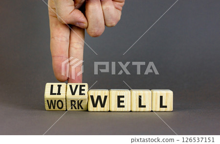 Live or work well symbol. Concept words Live well Work well on wooden cubes. Beautiful grey table grey background. Businessman hand. Business and live or work well concept. Copy space. Live or work well symbol. Concept words Live well Work well on wooden cubes. Beautiful grey table grey background. Businessman hand. Business and live or work well concept. Copy space. 126537151
