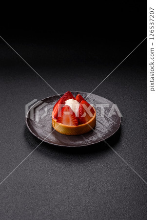 Round sweet tart with strawberry pieces and cream 126537207