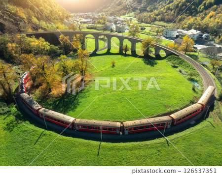 Aerial view of red train on Kreisviadukt Brusio in mountains 126537351