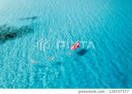 Aerial view of Inflatable pink flamingo with people on blue sea Aerial view of Inflatable pink flamingo with people on blue sea 126537377