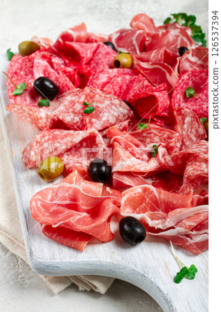 Assorted, meat appetizer, prosciutto, salami and ham, with olives , on a wooden white board, light background, breakfast, top view, close-up, no people 126537394