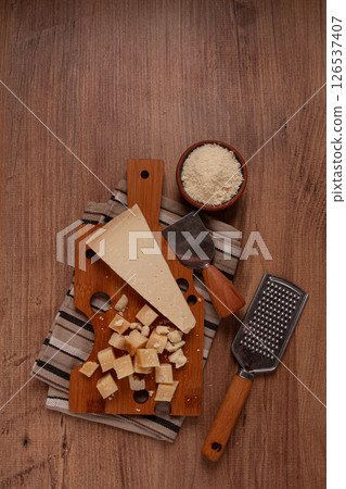 Freshly sliced and grated cheese, parmesan cheese, on a wooden chopping board, rustic style, no people 126537407