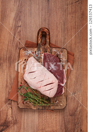 Fresh raw duck breasts, on a wooden chopping board, with herbs and spices, no people 126537413