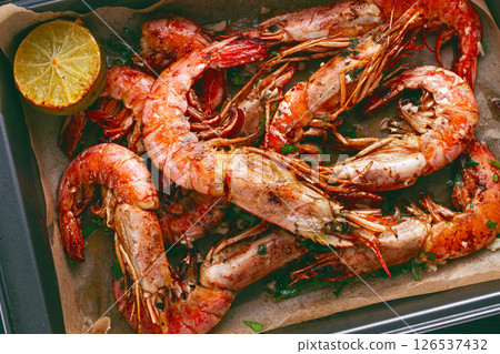 Juicy grilled shrimp, placed on a baking sheet lined with parchment paper, garnished with herbs and lemon. Juicy grilled shrimp, placed on a baking sheet lined with parchment paper, garnished with herbs and lemon. 126537432