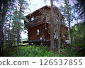 Rustic wooden cabin in the middle of a dense forest. 126537855