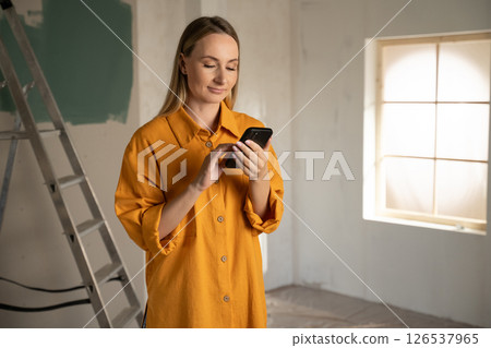 Woman in construction setting using smartphone 126537965