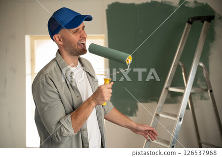 Painter singing with paint roller during home renovation 126537968