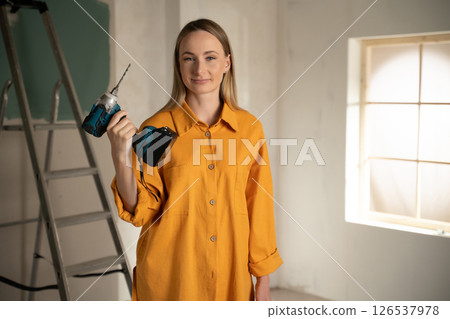 Woman holding cordless drill doing home renovation work Woman holding cordless drill doing home renovation work 126537978