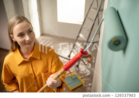 Woman painting wall with roller in new apartment renovation project Woman painting wall with roller in new apartment renovation project 126537983