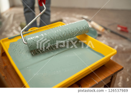 Painting roller with green paint in yellow tray 126537989