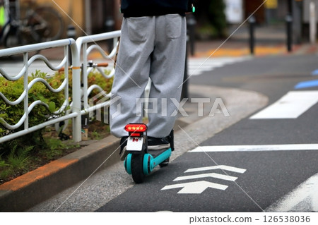 An electric kick scooter traveling on the road 126538036