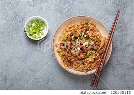 Dan dan noodles served with chopsticks and green onions top view, traditional Chinese Sichuan dish Dan dan noodles served with chopsticks and green onions top view, traditional Chinese Sichuan dish 126538118