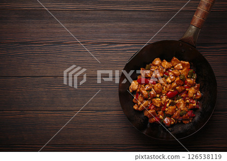 Traditional Chinese dish kung pao chicken in wok pan on wooden background top view. Space for text 126538119