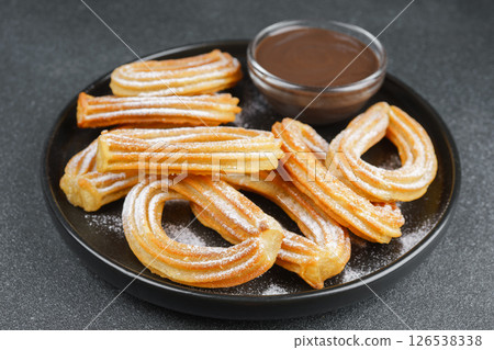 Traditional spanish dessert churros, fried dough pastry and chocolate sause on black background Traditional spanish dessert churros, fried dough pastry and chocolate sause on black background 126538338