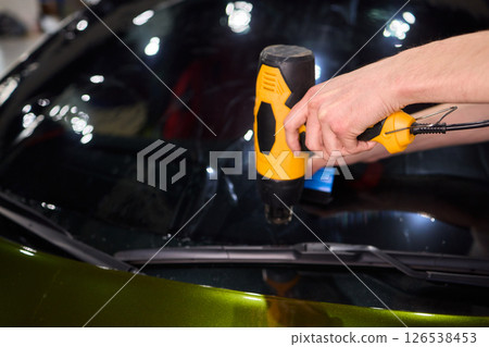 The Professional Windshield Tinting Process Conducted in a Modern Auto Showroom Environment The Professional Windshield Tinting Process Conducted in a Modern Auto Showroom Environment 126538453