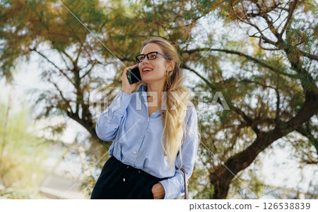 A young woman is engaged in a cheerful phone conversation while enjoying the great outdoors A young woman is engaged in a cheerful phone conversation while enjoying the great outdoors 126538839