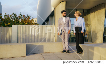 A group of professionals walking in a vibrant urban environment, showcasing teamwork A group of professionals walking in a vibrant urban environment, showcasing teamwork 126538843