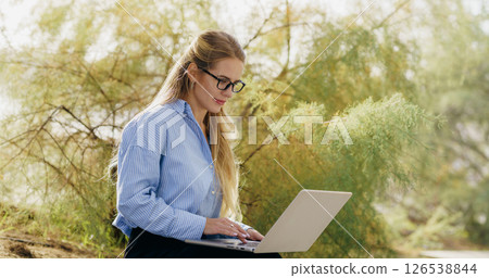 A businesswoman works on her laptop outdoors, balancing her career and personal life A businesswoman works on her laptop outdoors, balancing her career and personal life 126538844