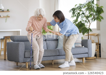 Care staff supporting a senior woman standing up with a cane Care staff supporting a senior woman standing up with a cane 126540423