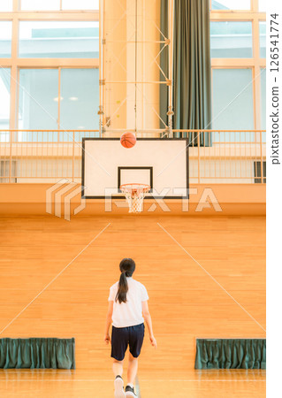 Junior high school and high school girls in gym clothes playing basketball in a gymnasium 126541774