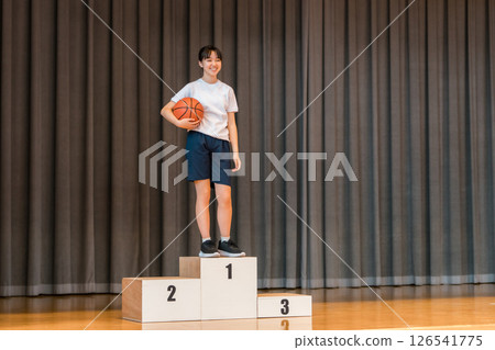 Elementary school, junior high school, and high school girls in gym clothes standing on the podium on the stage of a gymnasium Elementary school, junior high school, and high school girls in gym clothes standing on the podium on the stage of a gymnasium 126541775
