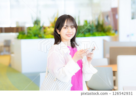 一個微笑的女人看著智能手機 一個微笑的女人看著智能手機 126542931