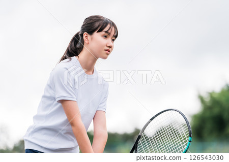 Elementary school, junior high school, and high school girls in gym clothes playing tennis in the schoolyard or on the grounds 126543030