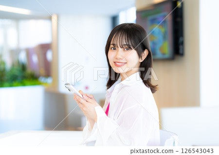 A young woman operating a smartphone A young woman operating a smartphone 126543043