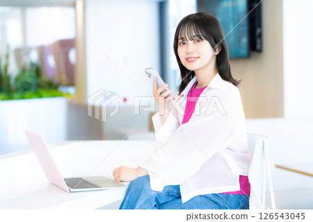 A young woman operating a smartphone 126543045