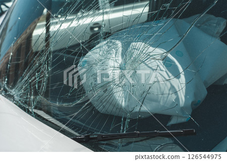 Broken windshield and deployed airbags of a car involved in a traffic accident 126544975