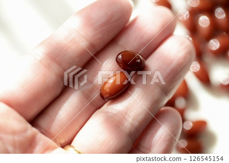 The hand of a woman in her 50s holding two placenta supplement tablets 126545154