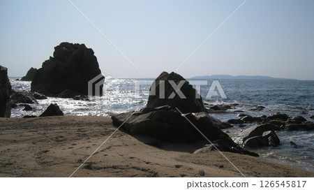 陽光下閃閃發光的日本海、藍天、島嶼、海灘上奇形怪狀的岩石 126545817