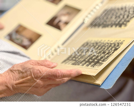 Elderly woman looking at group photos in a photo album Elderly woman looking at group photos in a photo album 126547231