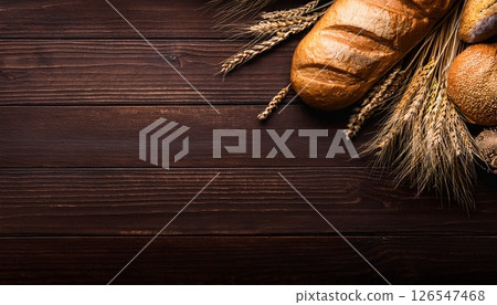 小麥和新鮮出爐的麵包在木紋上閃閃發光，複製空間 1 126547468
