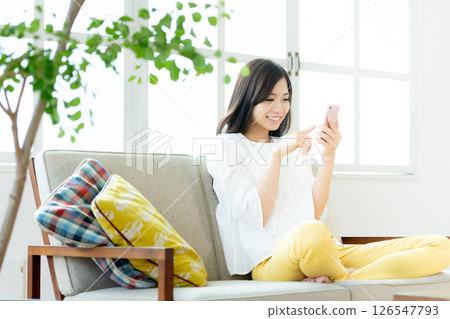 A young woman operating a smartphone in the living room A young woman operating a smartphone in the living room 126547793