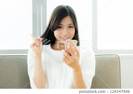A young woman operating a smartphone in the living room A young woman operating a smartphone in the living room 126547846