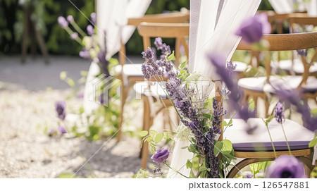 Aisle with wooden chairs and purple lavender floral decorations at an outdoor wedding ceremony in the garden 126547881