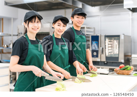 Male and female kitchen staff cutting cabbage in the kitchen Male and female kitchen staff cutting cabbage in the kitchen 126548450