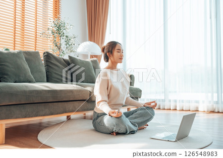 Happy young Asian woman practicing yoga and meditation at home sitting on floor Happy young Asian woman practicing yoga and meditation at home sitting on floor 126548983