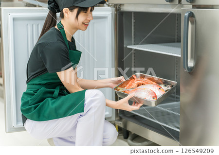 一名女廚房工作人員從冰箱取出食材 一名女廚房工作人員從冰箱取出食材 126549209