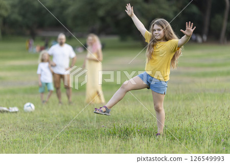 Girl dancing in the park with family watching in background 126549993