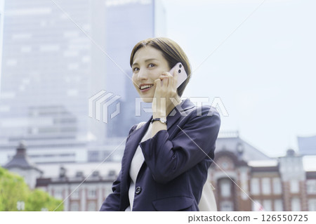 一位年輕女商人在東京車站前用智慧型手機聊天 一位年輕女商人在東京車站前用智慧型手機聊天 126550725