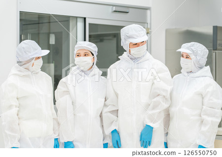Male and female staff working in a manufacturing plant wearing protective clothing and clean wear 126550750
