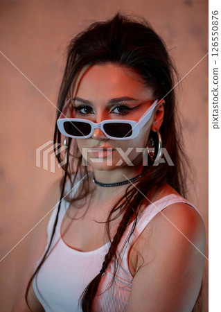A Stylish Portrait of a Confident Young Woman Dressed in Trendy Sunglasses and Fashionable Attire A Stylish Portrait of a Confident Young Woman Dressed in Trendy Sunglasses and Fashionable Attire 126550876