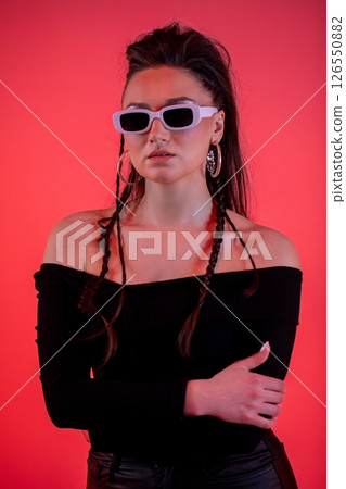 A Stylish and Chic Model Wearing Stylish Sunglasses Posed Stylishly Against a Bold Red Background 126550882