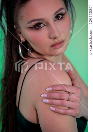 A Stylish and Captivating Portrait with Bold Makeup and a Striking Green Background 126550894