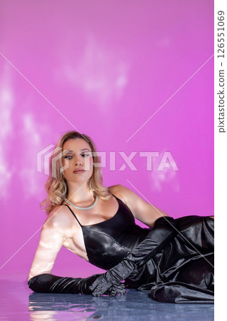 An Elegant Model Dressed in an EyeCatching Black Dress Set Against a Vibrant Pink Background An Elegant Model Dressed in an EyeCatching Black Dress Set Against a Vibrant Pink Background 126551069